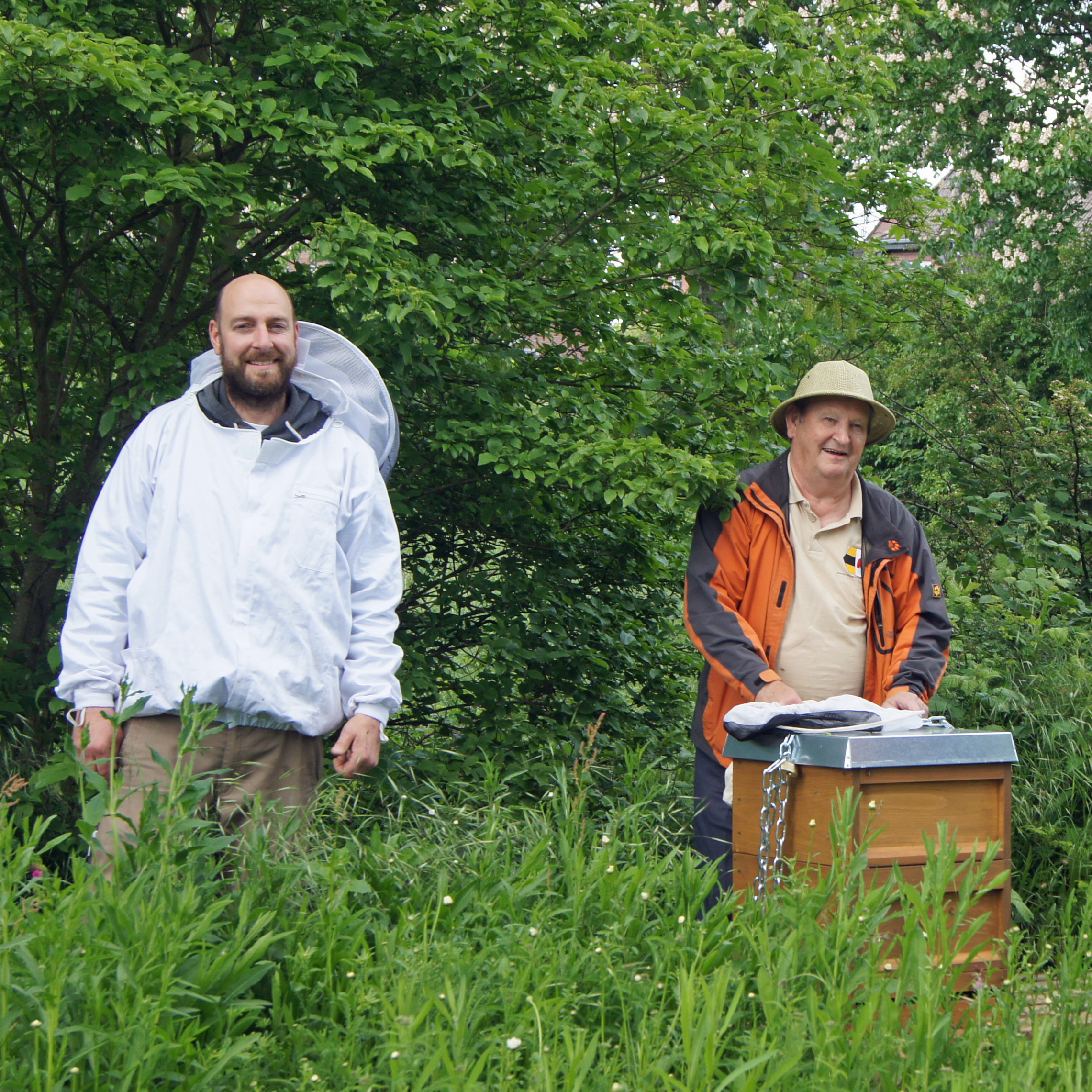 Zwei Männer stehen vor einem Bienenstock